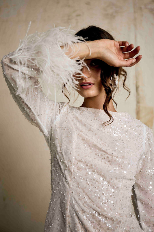 Long sleeve sequin party dress with feather detail on sleeve and hem